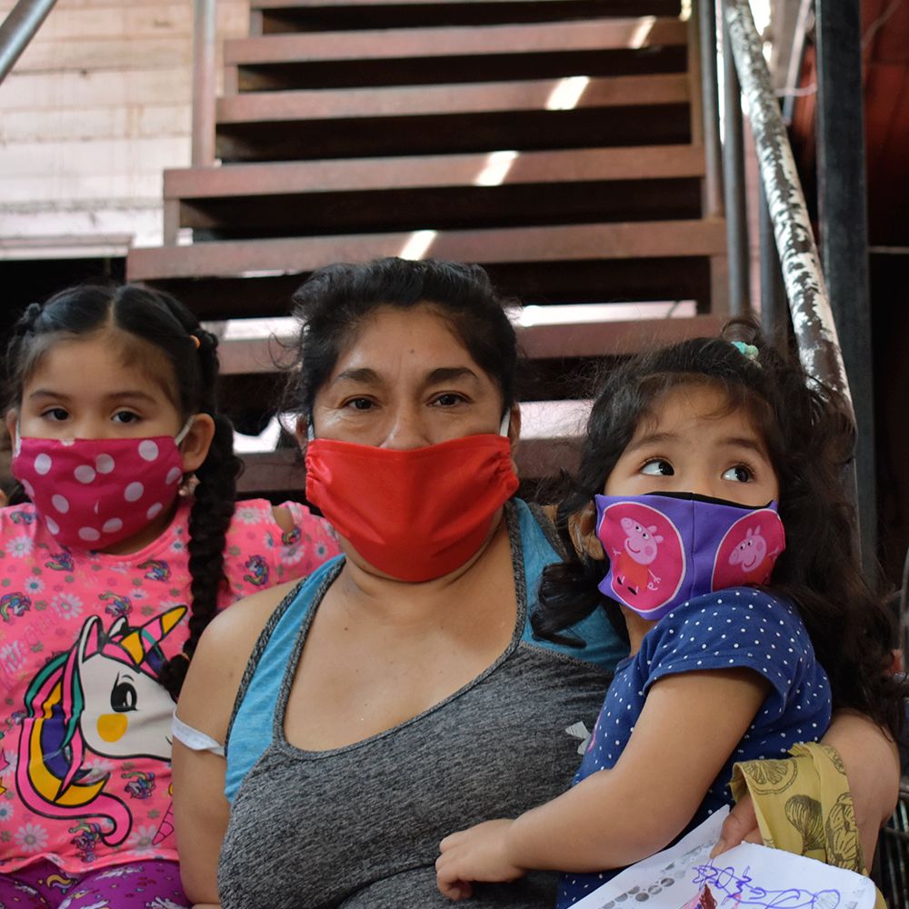 Una madre con sus hijas pequeñas sentadas en la escalera de la sede