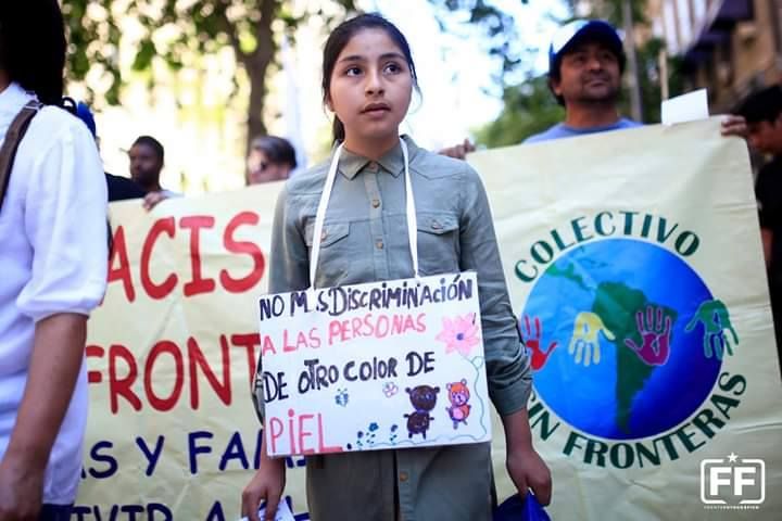 Una niña en una marcha sostiene un cartel que dice No más discriminación a las personas de otro color de piel